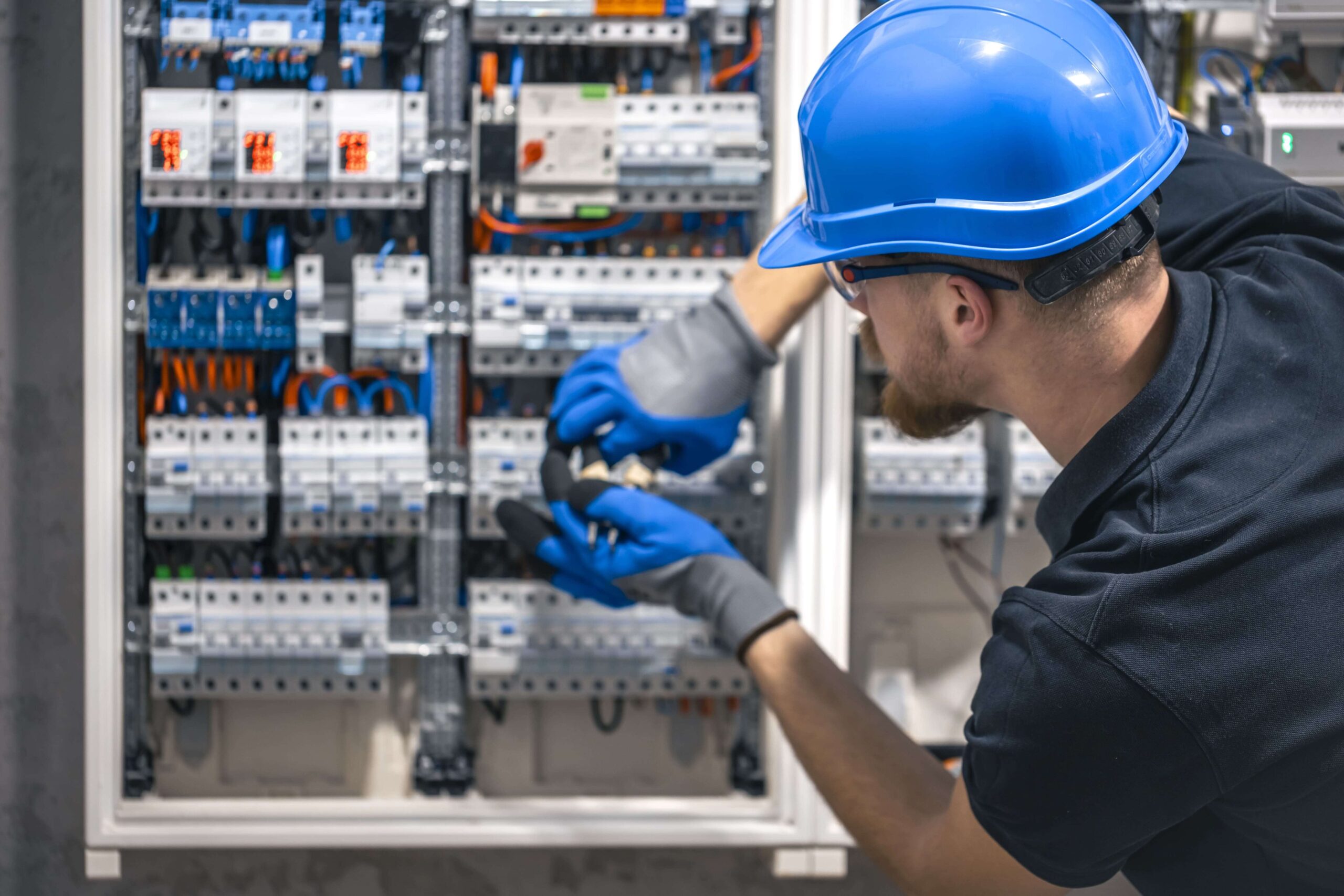 a-male-electrician-works-in-a-switchboard-with-an-2024-04-04-02-15-00-utc